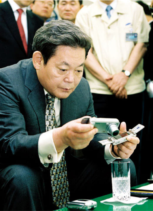 A photo of Chairman Lee Kun-hee inspecting digital cameras and mobile phones at the 2003 Advanced Products Exhibition.