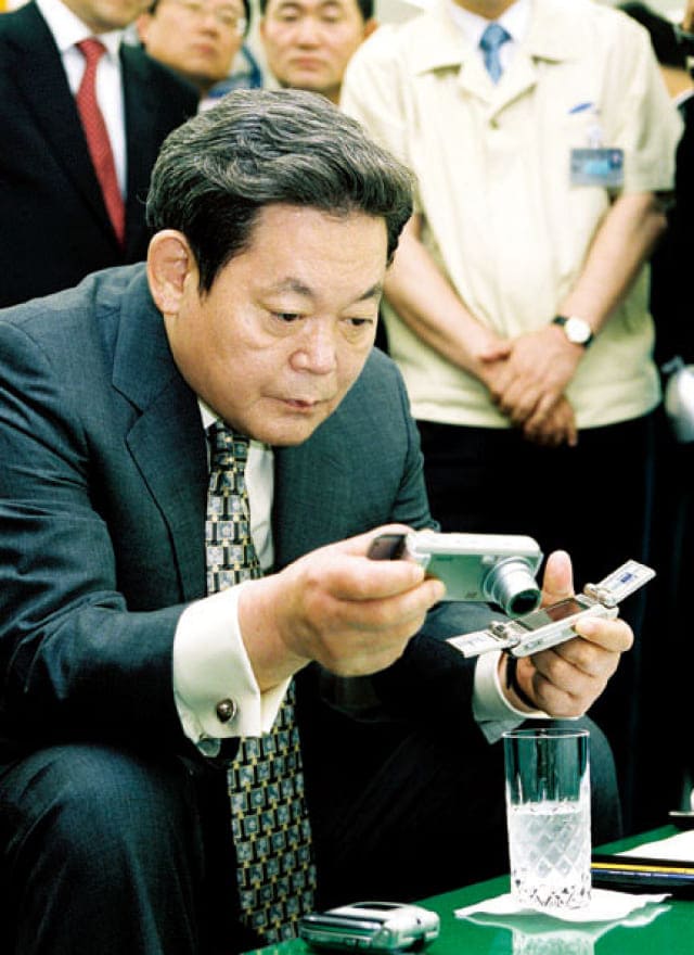 A photo of Chairman Lee Kun-hee inspecting digital cameras and mobile phones at the 2003 Advanced Products Exhibition.