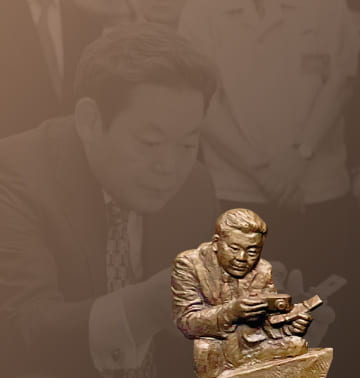 A photo and relief of Chairman Lee Kun-hee inspecting digital cameras and mobile phones at the 2003 Advanced Products Exhibition.