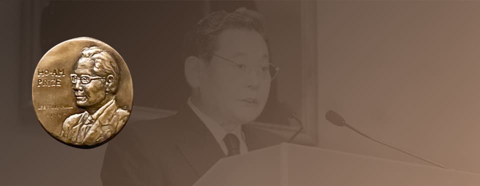 A relief of the Ho-Am Prize medal featuring founder Lee Byung-chul, and a background photo of Chairman Lee Kun-hee giving a memorial ceremony speech.